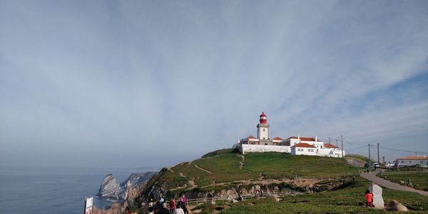 Lighthouse amidst sea and buildings against sky