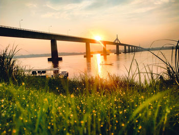 Bridge over river against sky during sunset