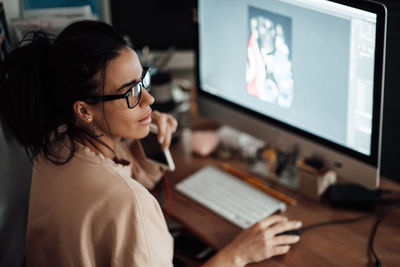 Midsection of woman using mobile phone while sitting on table