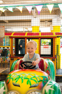 Portrait of smiling boy sitting at store