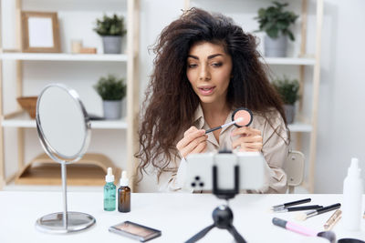 Woman filming make-up tutorial on smart phone at home