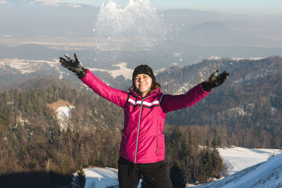 Woman playing with snow against mountains