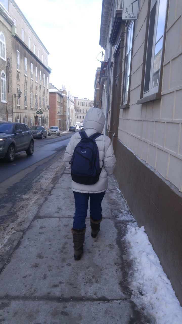 REAR VIEW OF MAN WALKING IN CITY