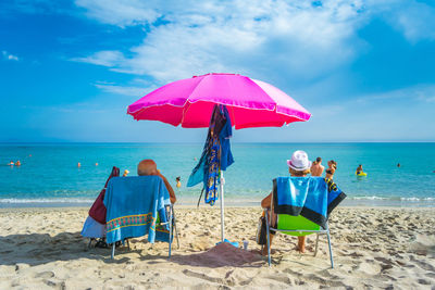 Deck chairs on beach against sky