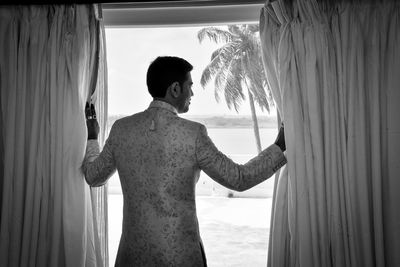 Rear view of woman standing by window