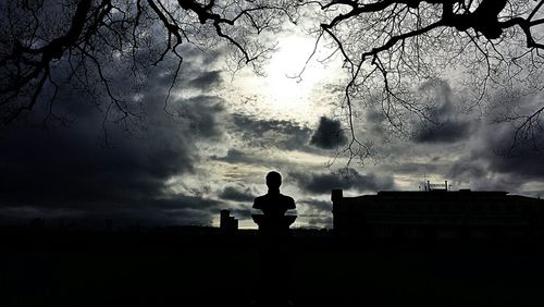 Low angle view of bare tree against cloudy sky