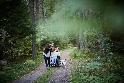 Male caretaker taking selfie with disabled woman in forest