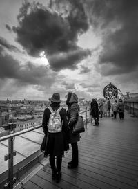 People at observation point against cloudy sky