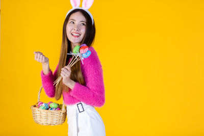 Young woman wearing mask against yellow background