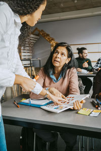 Mature female student discussing with teacher in classroom of university