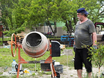 Mature caucasian man mixes cement mortar in concrete mixer