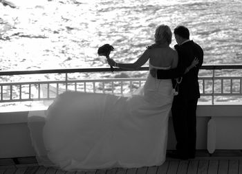 Couple standing at railing against sea