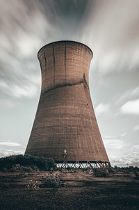 Low angle view of smoke stack on field against sky