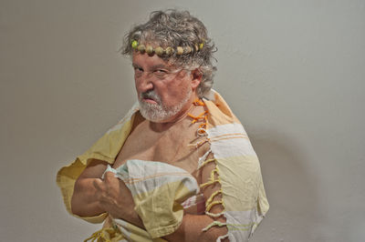 Portrait of man holding umbrella against wall