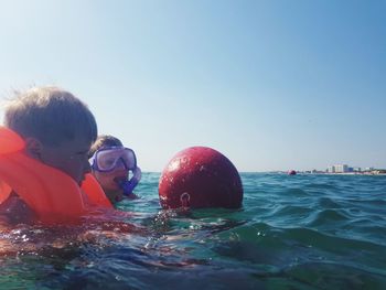 Portrait of boy swimming in pool against sea