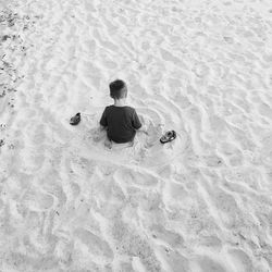 High angle view of boy sitting on sand at beach