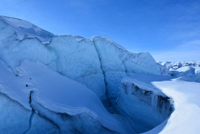 Scenic view of snowcapped mountains against blue sky