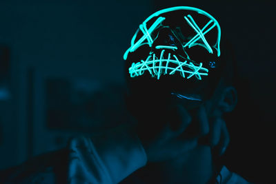 Close-up of man wearing glowing cap standing in darkroom
