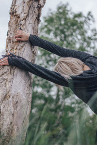 Midsection of woman with tree trunk in background