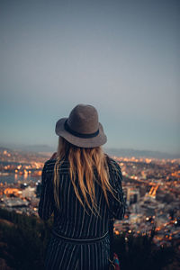 Rear view of woman standing by cityscape against sky