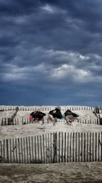 Fence on beach against sky