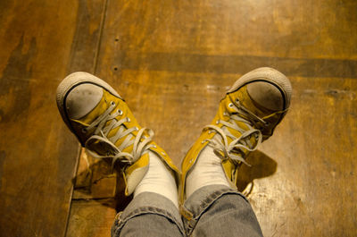 Low section of person wearing shoes standing on wooden floor