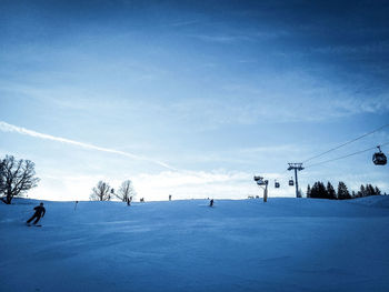 View of people skiing on snowcapped mountain against sky