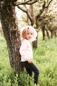 Cute girl standing by tree trunk in park