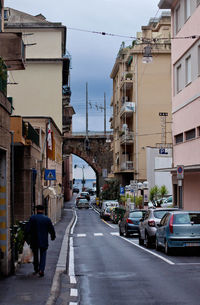 Man walking on roadside by parked cars in city