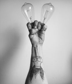 Close-up of man hand holding light bulbs against wall