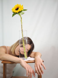 Midsection of woman holding flower while sitting on plant