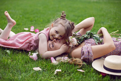 Beautiful young mother with daughter in pink dresses lie on a green meadow in summer. pet rabbit