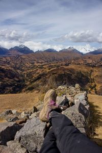 Low section of person on rock against sky