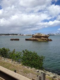 Boats in sea against cloudy sky