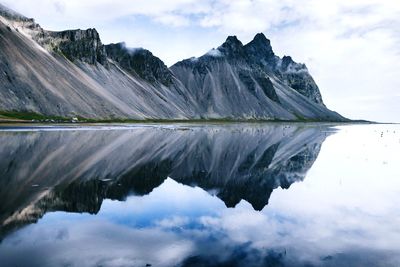 Scenic view of lake and mountains against cloudy sky