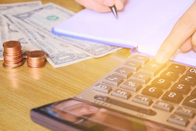 Close-up of hand holding coins on table