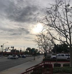 Cars on street in city against sky at sunset