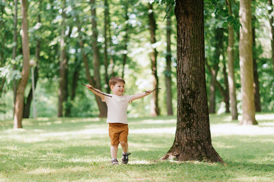 Little caucasian boy playing outdoors in the park with a stick from a tree