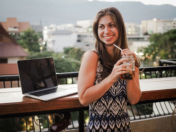 Portrait of smiling young woman using laptop on table