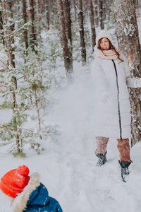 Mom and son play snowballs in the winter forest. mom walks with her son in a snowfall in the forest.