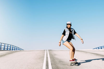Woman skateboarding against blue sky