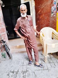 Full length portrait of woman standing against building