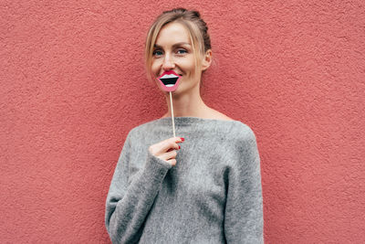 Portrait of a smiling young woman against wall