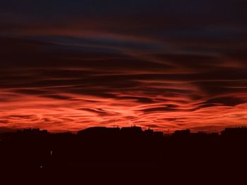 Silhouette landscape against dramatic sky during sunset