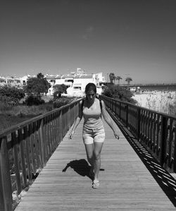 Full length of woman on footbridge against sky