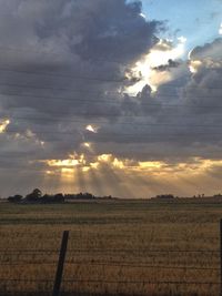 Scenic view of landscape against cloudy sky at sunset