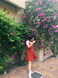 Woman standing by pink flowering plants