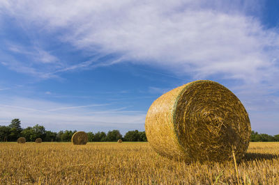 Hay bales on field against sky