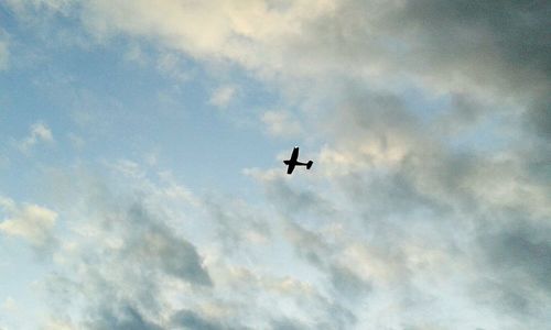 Low angle view of airplane flying against cloudy sky