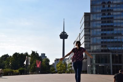 Young woman with umbrella standing in city against sky